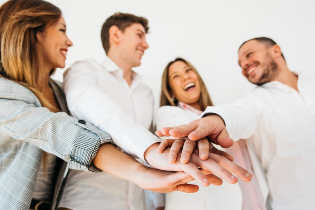companeros-trabajo-sonrientes-oficina-que-ponen-manos-juntas